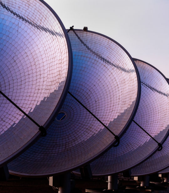 several large satellite dishes are lined up in a row