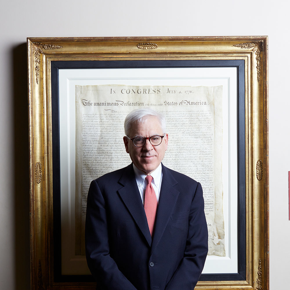 David M. Rubenstein standing in front of a copy of the U.S. constitution