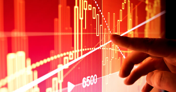 Finger pointing at market data on a large display screen