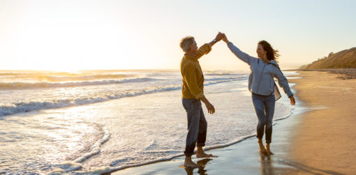 a couple walks on the beach holding hands