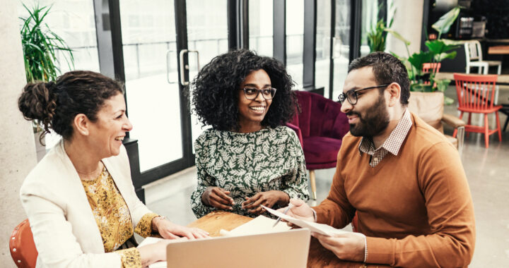 A couple smiles as they discuss plans with their advisor at a table