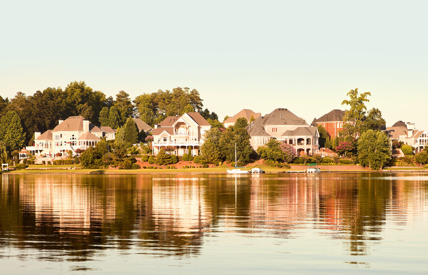 A row of luxury homes reflected in a lake.
