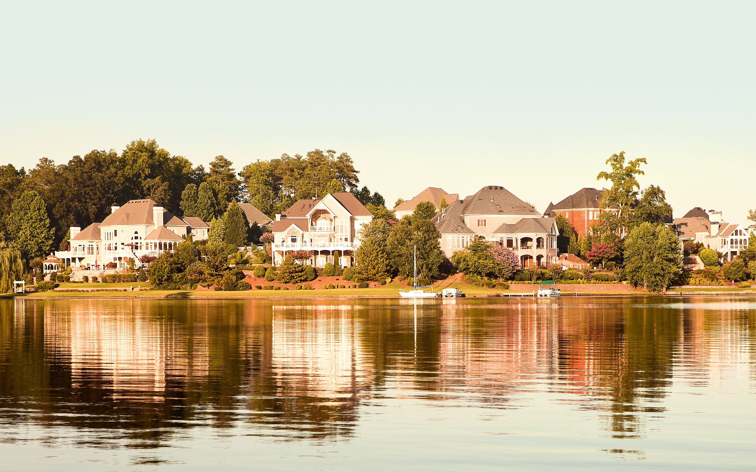 A row of luxury homes reflected in a lake.