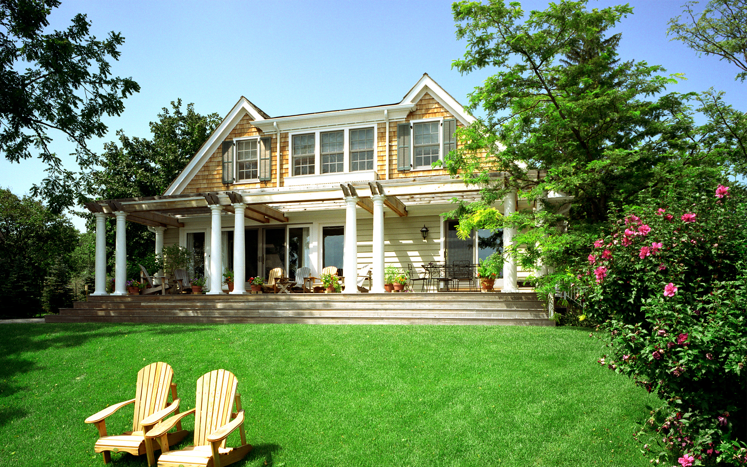 Adirondack chairs in front of a large yellow house with white columns