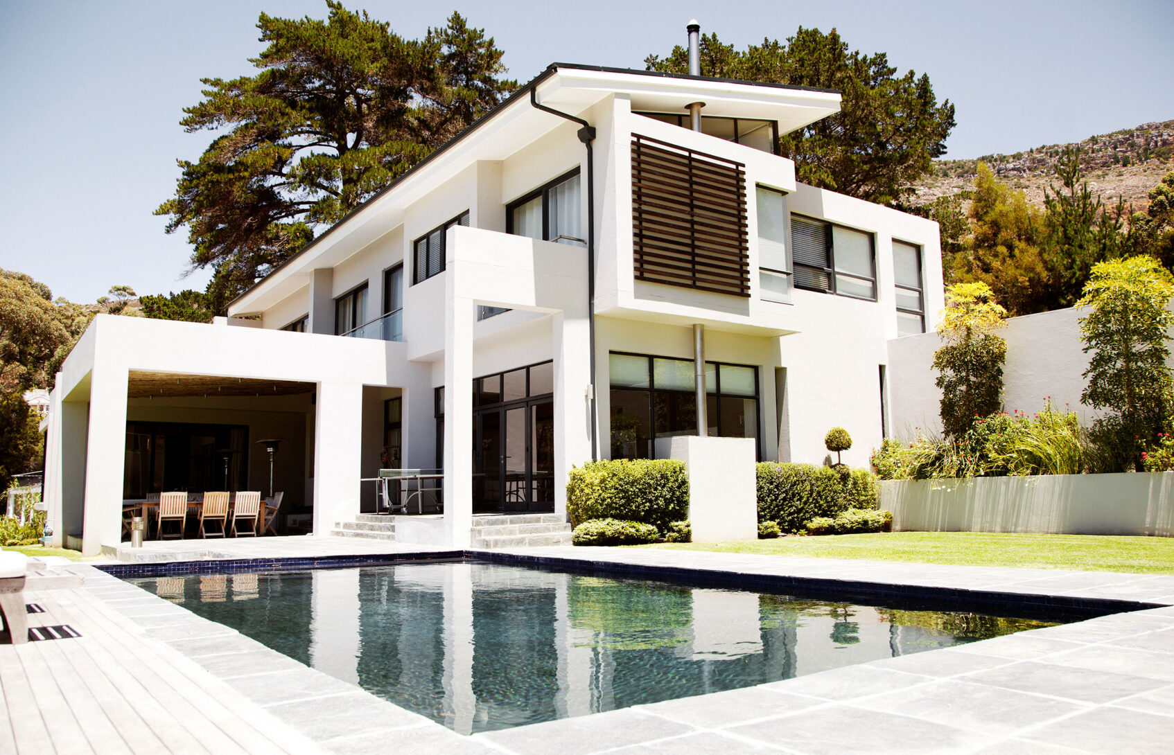 A modern, two-story international-style house with a covered patio and a pool