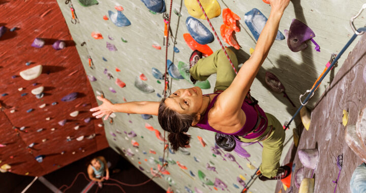 A woman climbing a colorful indoor rock wall
