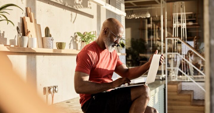 Man in his 50s seated with laptop inside a home