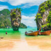 Two decorative long-tail fishing boats float in the water in Phang Nga Bay, Thailand.