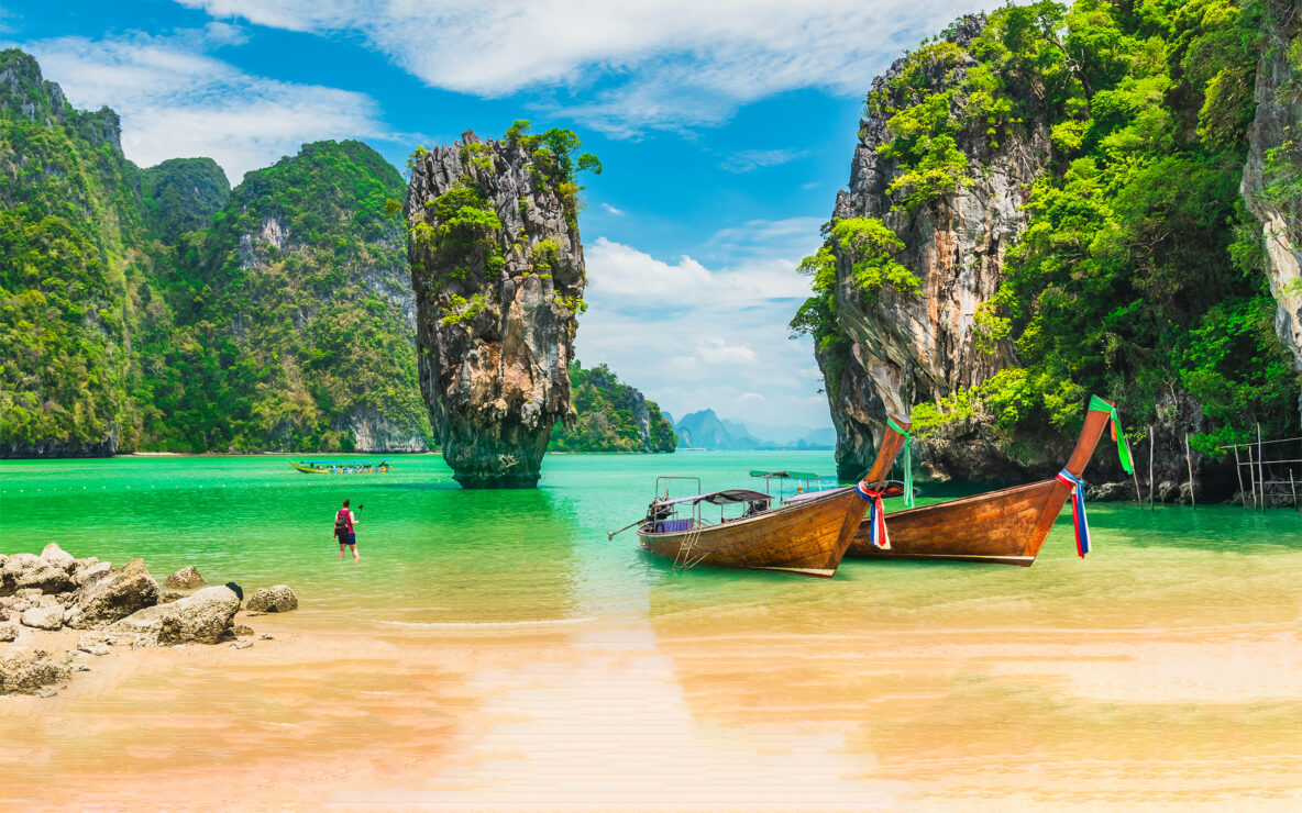 Two decorative long-tail fishing boats float in the water in Phang Nga Bay, Thailand.