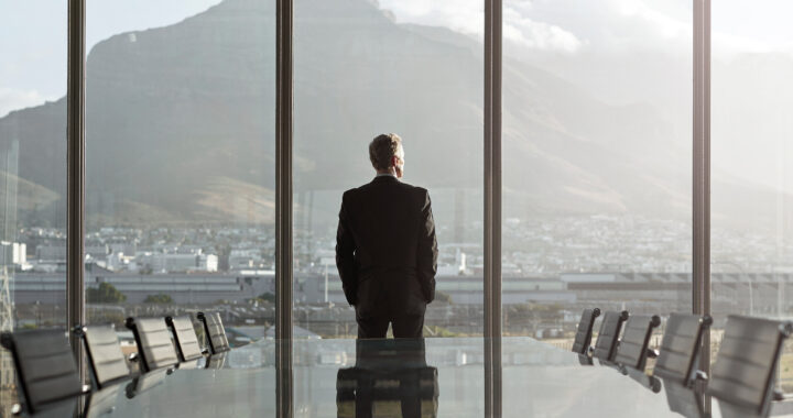 Businessman standing in office looking out the window.