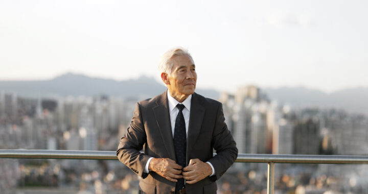 A businessman standing on balcony with city skyline in the background.