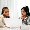 Mother and teenage daughter looking at paperwork at home.