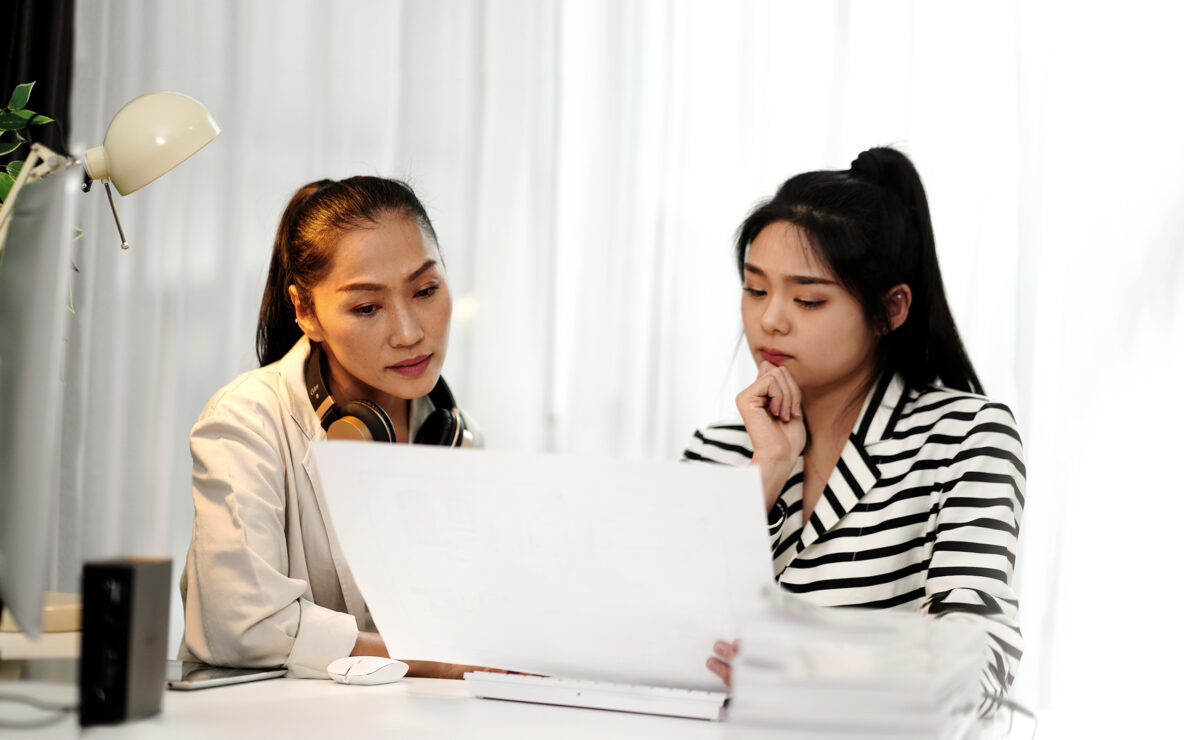 Mother and teenage daughter looking at paperwork at home.