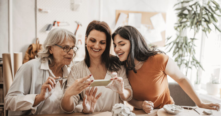 Multigenerational family women taking pictures of their pottery artwork with smartphone.