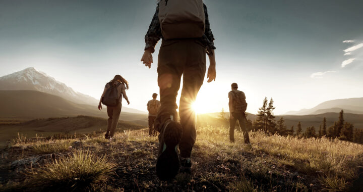 Group of sporty people walks in mountains at sunset