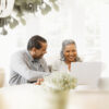 A husband and wife looking at a computer screen and smiling.