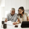 A couple sitting at their kitchen counter reviewing their finances.