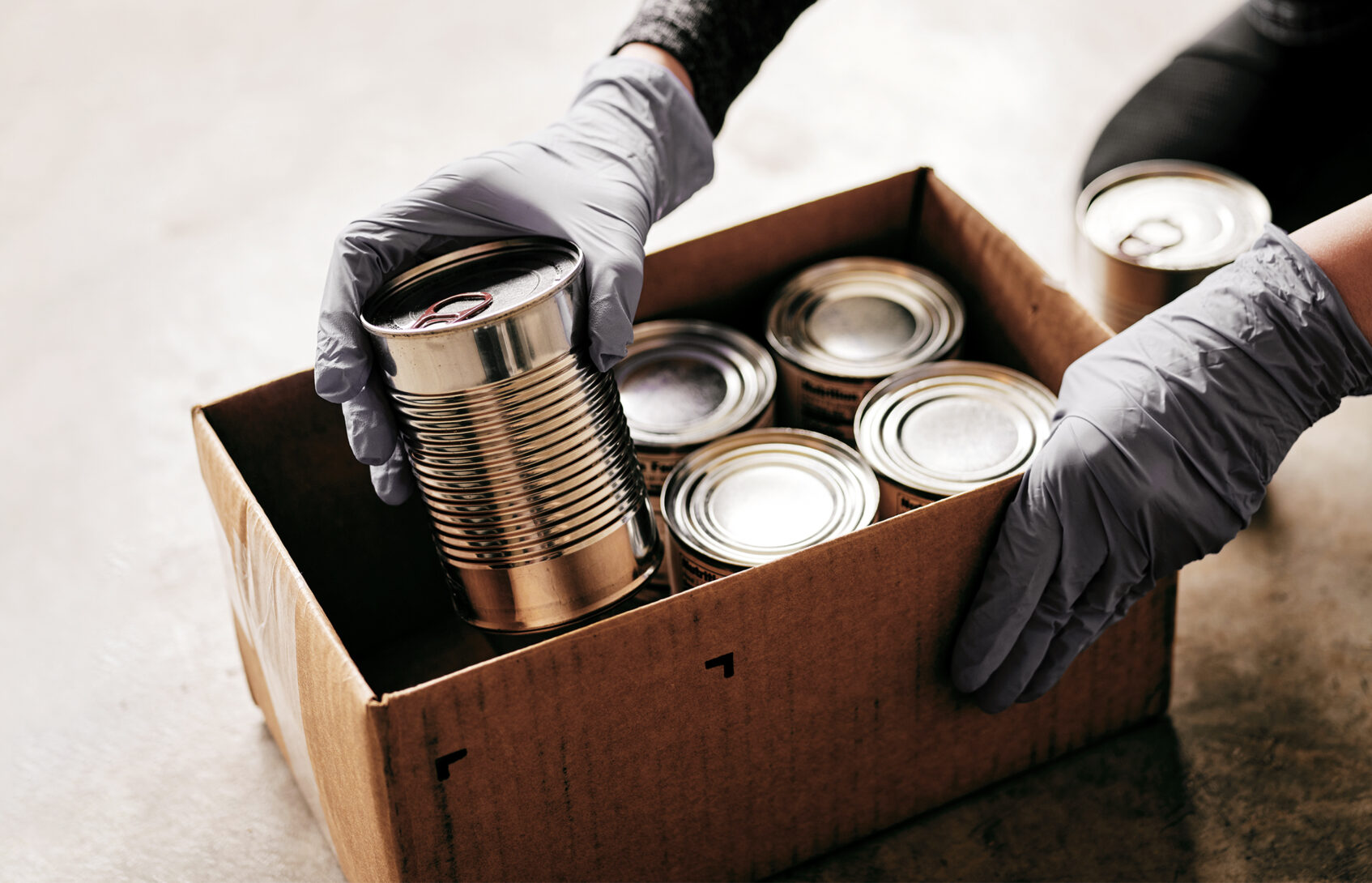 Volunteer preparing donation boxes with cans at the food bank