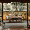 A multigenerational family seated around a table in the backyard.