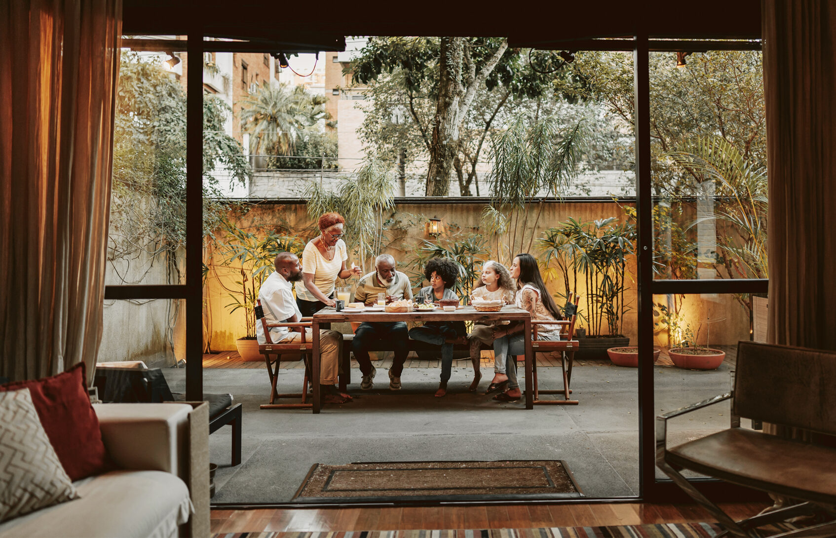 A multigenerational family seated around a table in the backyard.