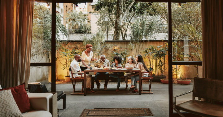 A multigenerational family seated around a table in the backyard.