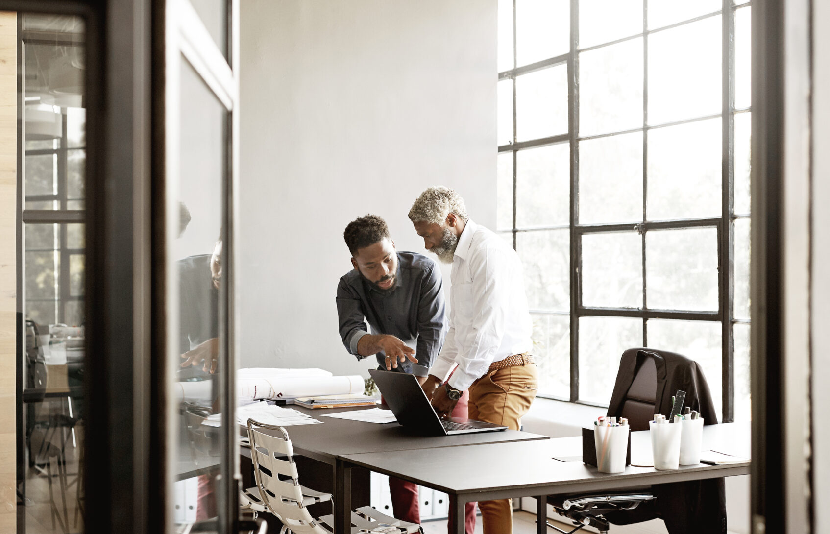 Businessmen in a meeting while standing over a desk.