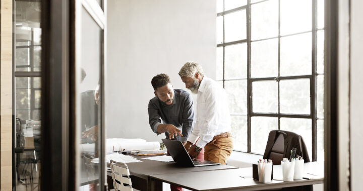 Businessmen in a meeting while standing over a desk.