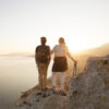A hiking couple pauses to enjoy a view of the water.