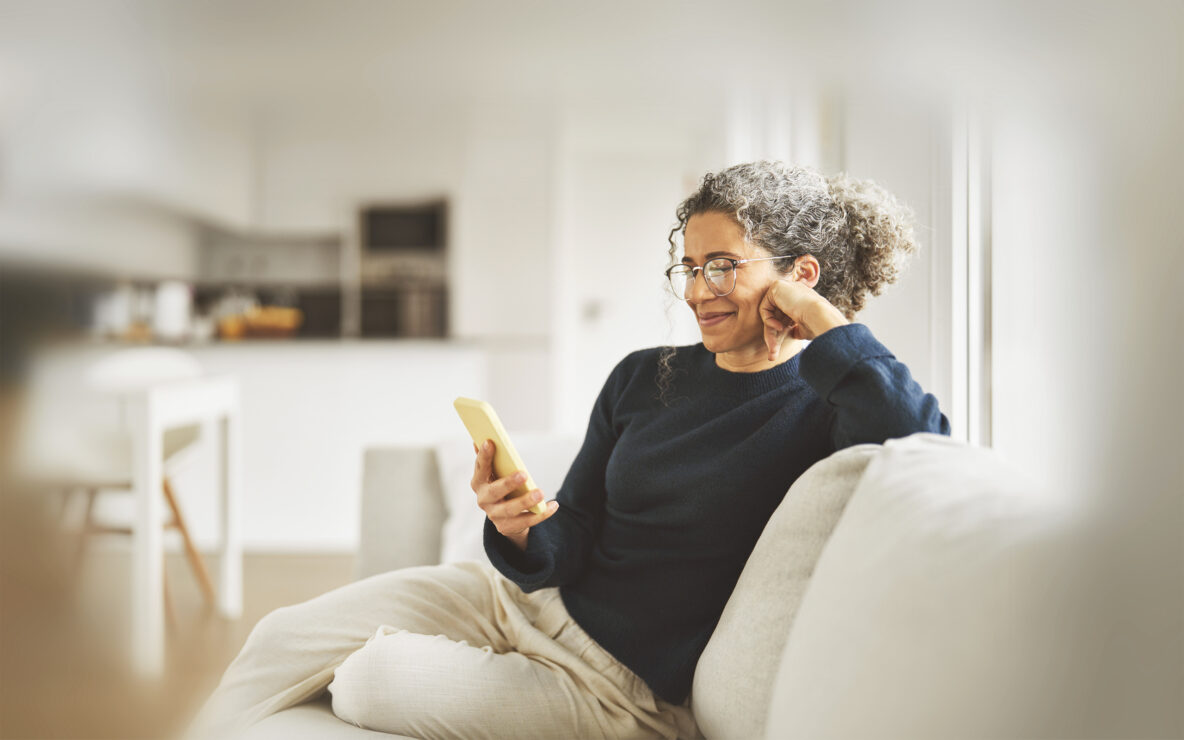 A happy woman sitting on the couch, looking at her phone