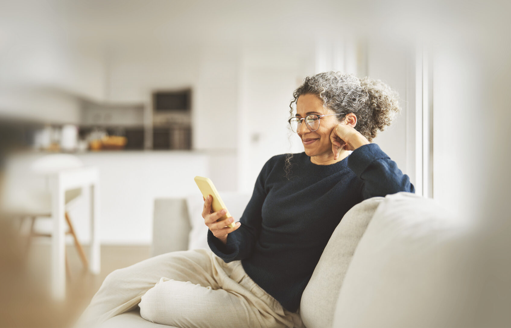 A happy woman sitting on the couch, looking at her phone