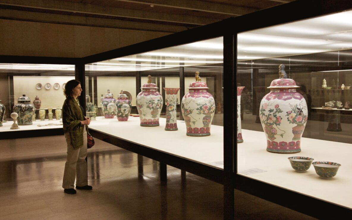 A woman views a series of floral urns at a museum exhibition