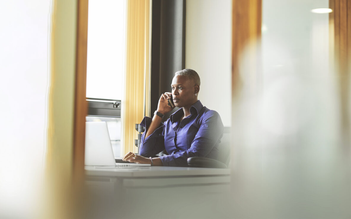 Woman seated at her desk with phone in hand